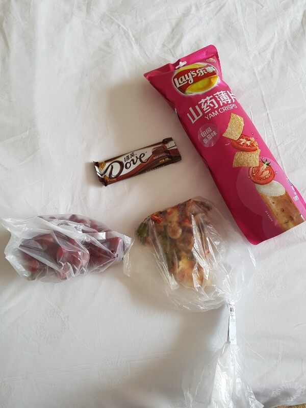 grocery store finds : a slice of pizza, grapes, yam crisps and a Dove chocolate bar 