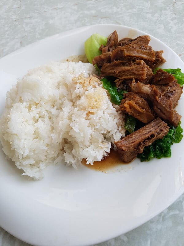 beef on a bed of lettuce and a pile of white rice next to it