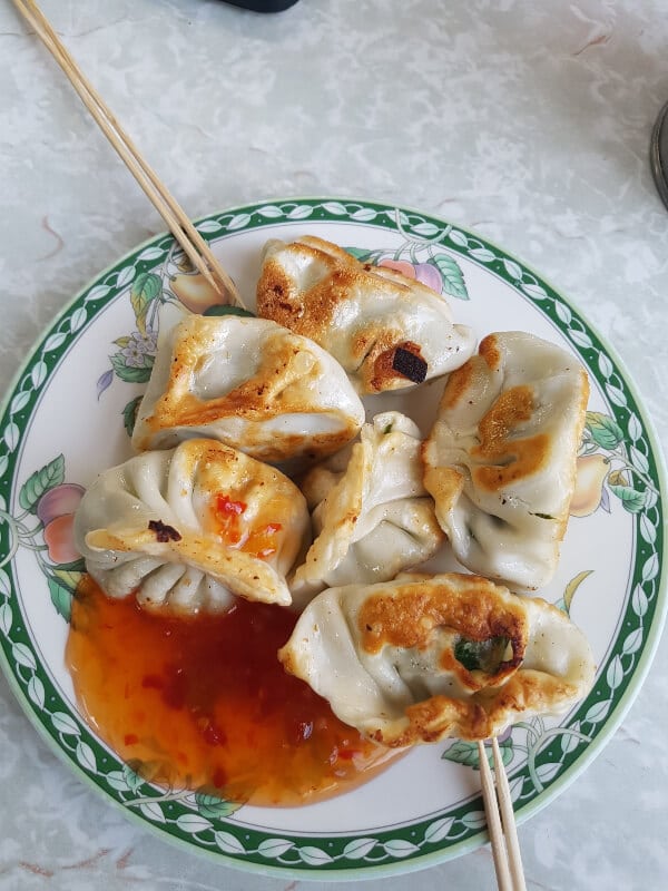 a plate of dumplings with an orange chili dipping sauce 