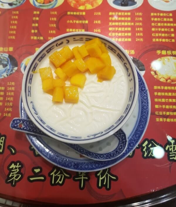 coconut milk pudding with mangoes served in a little blue and white bowl 