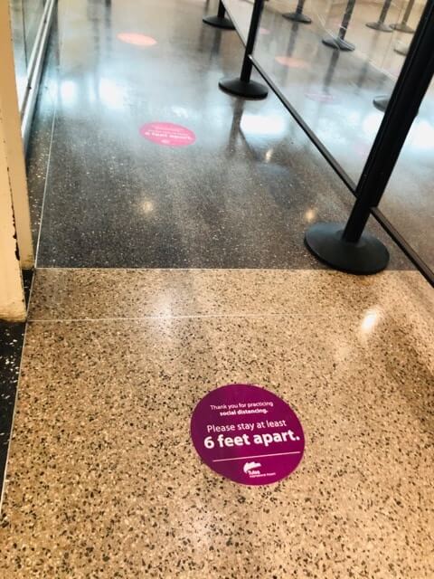 Showing the stickers on the floor of the airport reminding people to stay six feet apart 