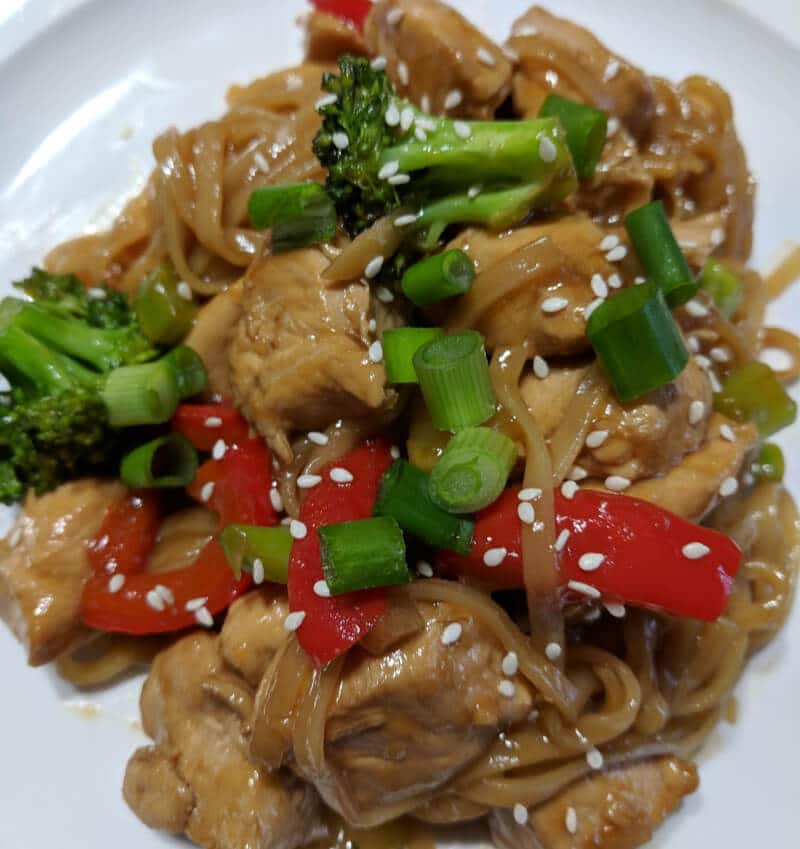 A plate of chicken teriyaki stir-fry recipe. It's topped with green onions and sesame seeds.
