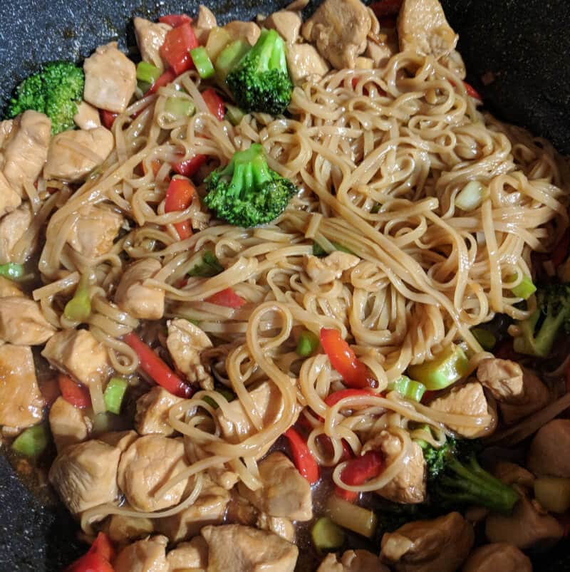 A close up shot of the chicken Teriyaki stir-fry. There is noodles, chicken, red peppers and broccoli. 