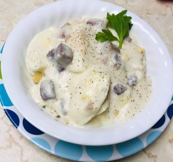 a bowl filled with eggs and ham in a cream sauce served over biscuits sprinkled with salt and pepper