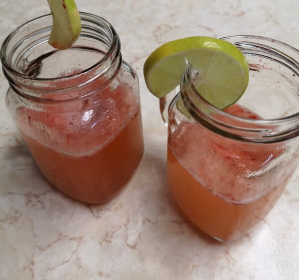 two glasses of strawberry limeade garnished with limes