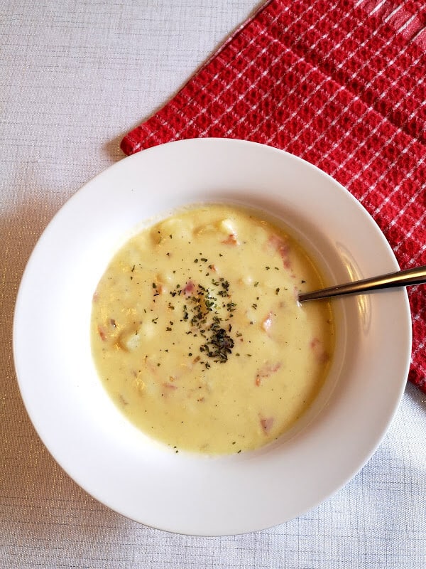 A bowl of Delicious Bacon and Potato Chowder garnished with dried parsley