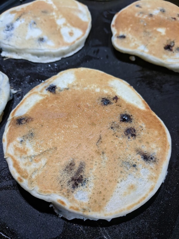 A few blueberry pancakes cooking on the grill.  