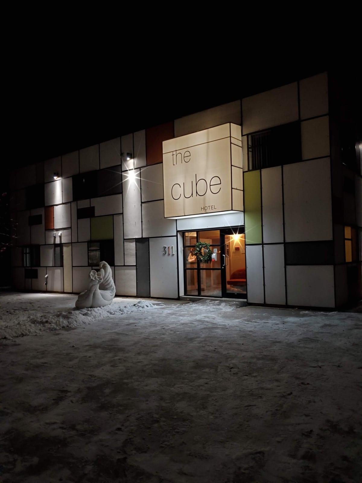 A photo outside the hotel we stayed at called The Cube hotel. It is in the shape of a cube, the outside decorated with rectangle tiles that are mostly white with a few other colors here and there.