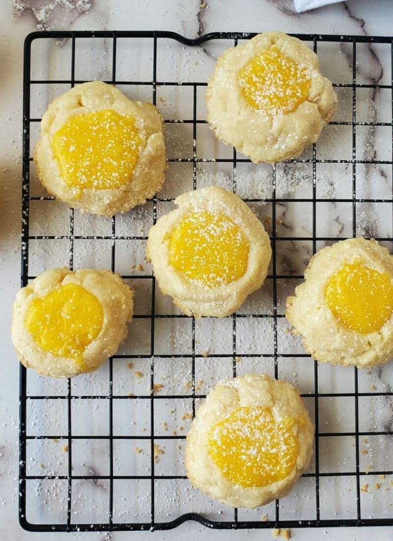 A wire rack filled with lemon curd cookies. The cookies are dusted with powdered sugar.