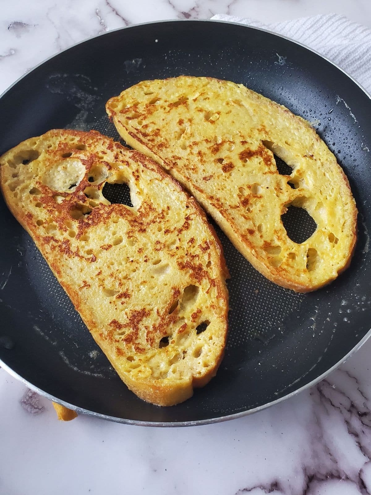 A frying pan with two slices of Sourdough French Toast in it.
