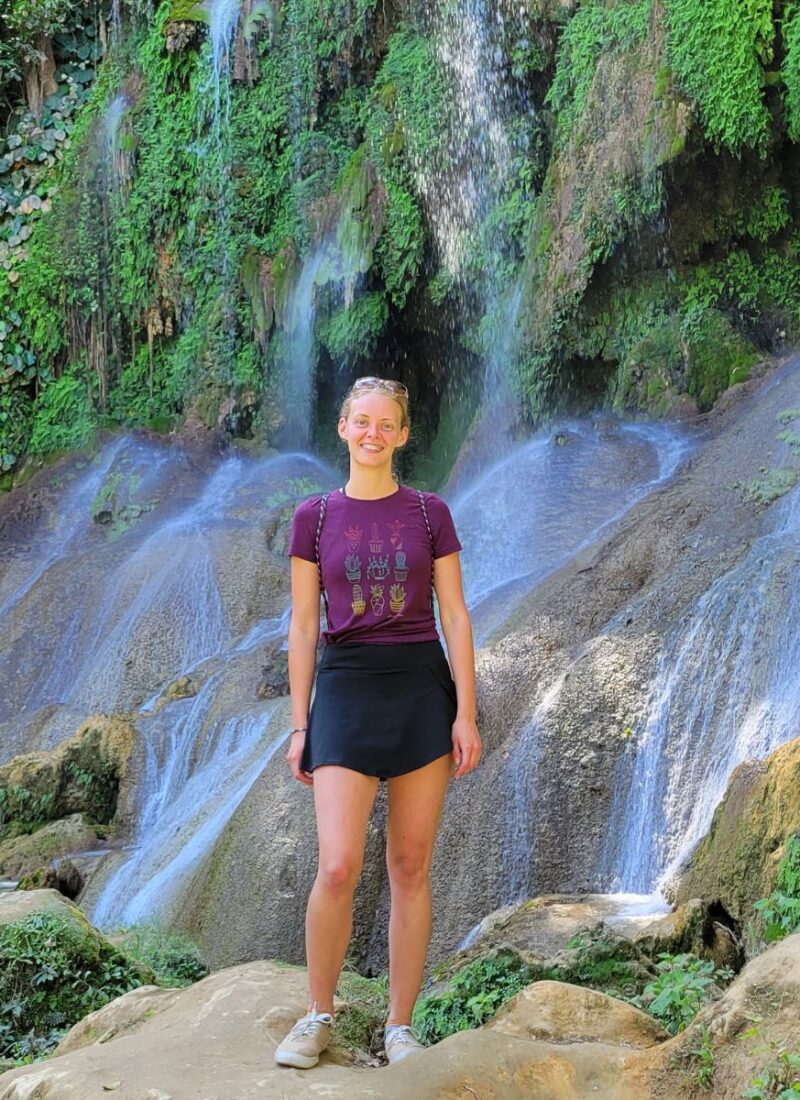 A blond girl standing in front of a waterfall in Cuba.